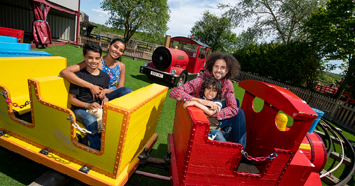 family smiling sat on train ride at Adventure Valley 